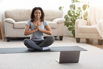 Sporty Woman Practicing Yoga Online With Instructor On Laptop At Home