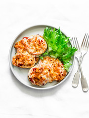 Roasted chicken chop with tomatoes, mushrooms and mozzarella on a light background, top view. Delicious healthy lunch