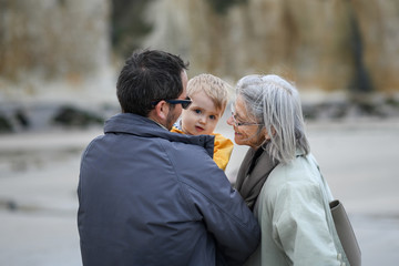 Gray-haired grandmother with a son and grandson on a walk