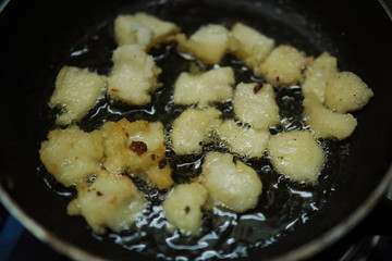 Onion vada with hot oil boiling in cooking pan closeup view, Indian dish making in a traditional home method , some area this is called ulli vada.