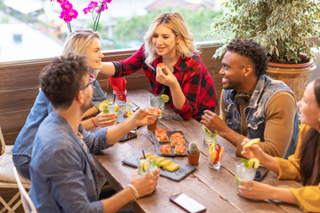 Multiracial group of young millennials friends talking and dining together - students party at...