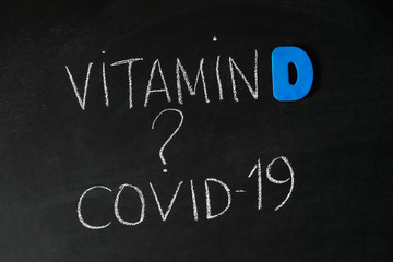 Fototapeta premium Vitamin D help in treating coronavirus. Vitamin D, coronavirus and question mark drawing on chalkboard