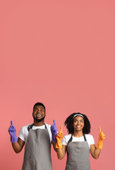 Cleaning Service Offer. Joyful Black Couple In Rubber Gloves Pointing Upwards