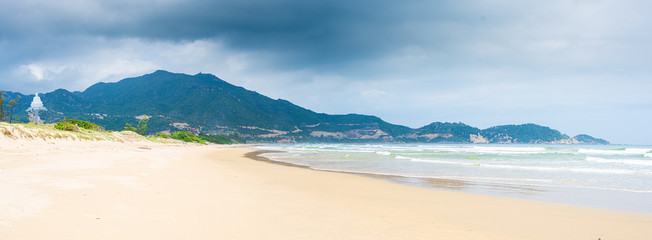 Secluded tropical beach turquoise transparent water dramatic clouds on mountains, Quy Nhon Vietnam central coast travel destination, desert white sand beach no people