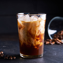 Tasty ice coffee with milk , cold drink in glass on dark background