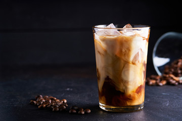 Tasty ice coffee with milk , cold drink in glass on dark background Copy space