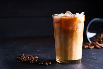 Tasty ice coffee with milk , cold drink in glass on dark background Copy space