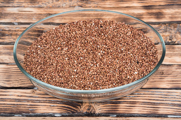 Buckwheat in a glass bowl. Raw buckwheat porridge.