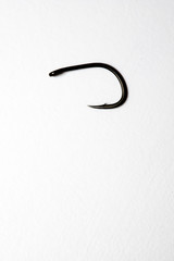 Single fish hook on a white background. Sharp point and barbed hook.