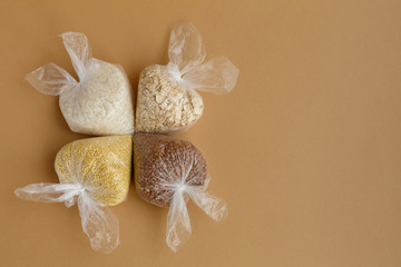 various groats in plastic bags on a brown background
