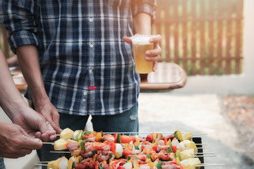 A man grilling pork and barbecue in dinner party. Food, people and family time concept.