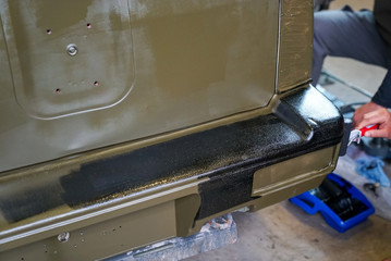 close up of a man painting an army jeep and adding black trim