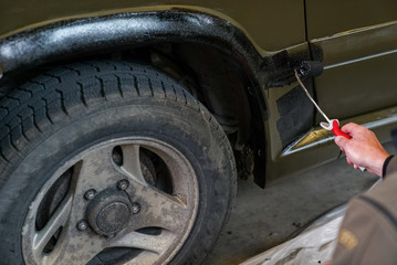 Fototapeta premium close up of a soldier painting an army jeep and adding black trim