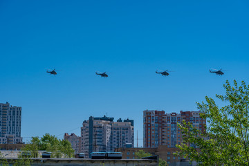 Four helicopters of russian air forces are flying in a row on bright blue sky