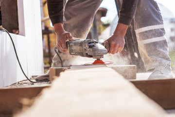 Man hands hold an old machine that grinds boards.