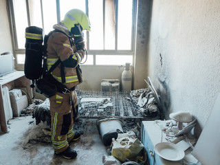 Firefighter with breathing apparatus examines fire on mattress
