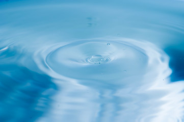 Naklejka na ściany i meble Water drops splash and circle reflextion background.Close up fresh water drops falling into the water and ripples of light blue.