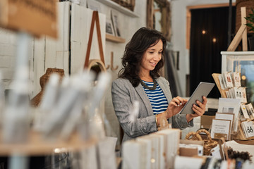 Smiling young Asian woman using a tablet in her shop