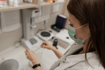 Tired pharmacist working during a coronavirus pandemic and wearing an anti-virus mask. Pharmacist taking care of capsules with medicines. COVID-19 Disease. Pharmacy store.