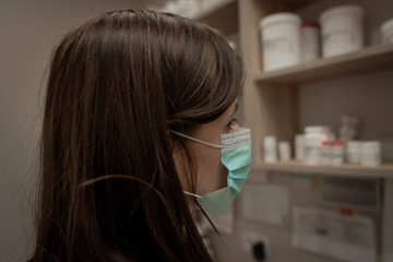 Closeup shot of tired pharmacist working during a coronavirus pandemic and wearing an anti-virus mask. Pharmacist looking for a medicines.