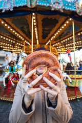 Fototapeta premium A sugary donut in front of an ancient German Horse Carousel built in 1896 in Navona Square, Rome, Italy