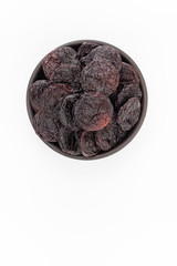 Dried plumps in round bowl on white background, top view