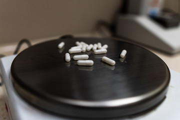 Capsules with medication inside lying on a pharmacy balance prior for administration to a sick patient for coronavirus during global pandemic.
