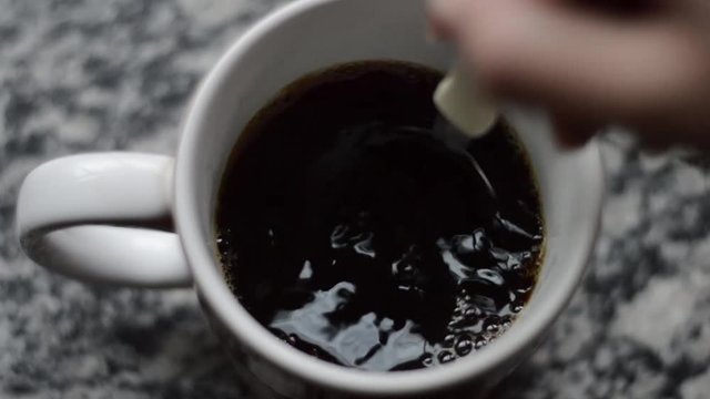 hand mixing coffee with a spoon, beautiful bubbles