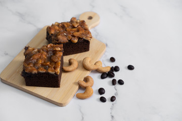 The square slice of toffee cake with cashew nut and caramel syrup on marble background.