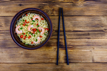 Instant noodle with shrimps, red pepper and green onion in a ceramic bowl. Japanese food. Top view