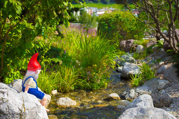 small waterfall in the garden with a gnome elf looking by on the river