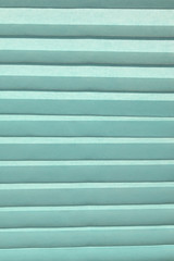 Fototapeta premium Background of blue pleated horizontal. Vertical format. The texture of the nonwoven fabric in the crease. Jalousie.