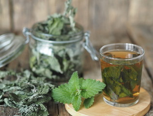 Medicinal herbal tea using dried Melissa. Dried leaves of Melissa or mint with a fresh twig and decoction in a glass on an wooden table.