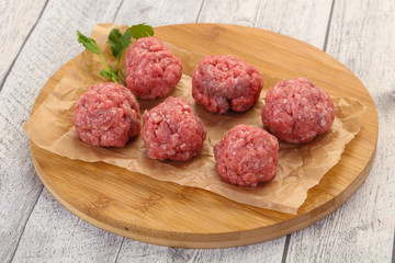 Raw meatball over wooden background