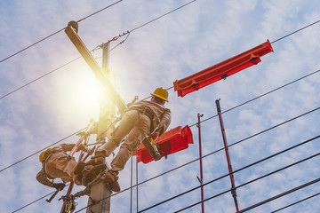 Two linesmen use insulated equipment to repair and maintain high-voltage distribution systems. The...