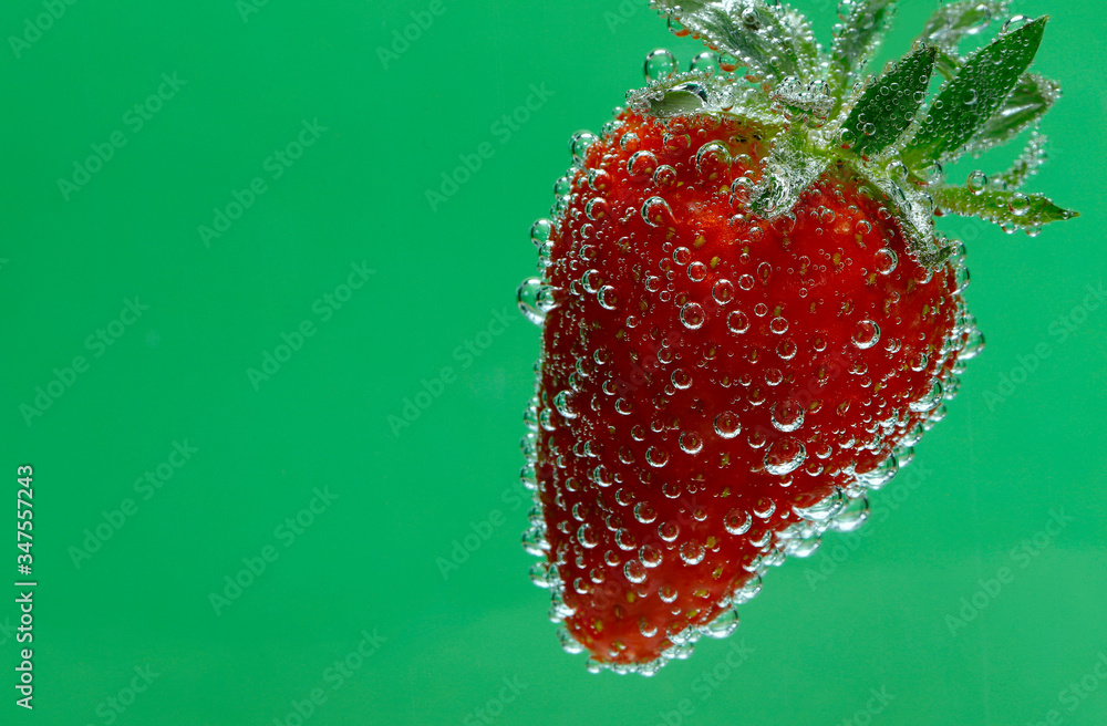 Wall mural Beautiful fruit background. Strawberry closeup. Texture of strawberries in bubbles on a green background. Horizontal, close-up, nobody, side view, free space. Healthy eating concept.