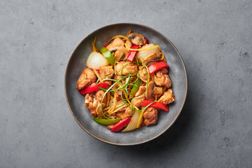 Thai Ginger Chicken or Gai Pad King in gray matte bowl on concrete backdrop. Gai Pad King is Thailand cuisine dish with chicken meat, ginger strips, onion, capsicum and sauces. Thai Food. Copy space