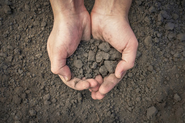 The farmer holds the soil in his hands on the background of the earth. close-up. Ecology concept. Hands hold the earth. Top view.