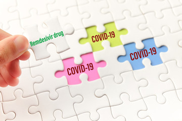 The drug remdesivir word on white jigsaw puzzle go to replace COVID-19 word on blue, green and purple gap - idea answer concept.