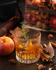 Whisky or bourbon with ice, branch of rosemary with smoke and apples, cinnamon sticks. Concept of...