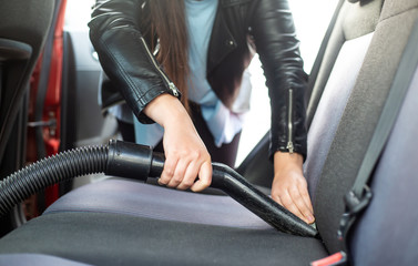 Woman cleaning, vacuuming interior of the car by vacuum cleaner, transport concept