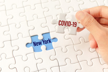 The COVID-19 word on white jigsaw puzzle go to replace New York word on blue gap - idea answer concept.