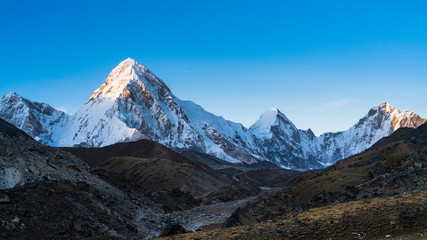 Fototapeta na wymiar Panoramic image of summits of Pumo Ri and Lingtren mountain peaks in Mahalangur Himalayan range in Sagarmatha National Park in Nepal. This is a UNESCO world heritage site. 