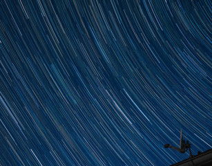 Satellitenantenne vor Nachthimmel mit Sternenspuren