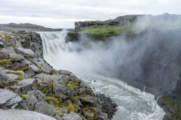 Northern europe most powerful waterfall, the dettifoss in Iceland during early morning hours. Soft light and cloudy sky with big mist swirls. Travelling, holiday and icelandic concept