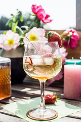 Cocktail on a wooden table in the sun with flowers and candles