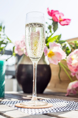 Champaign on a wooden table in the sun with flowers and candles