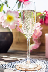 Champaign on a wooden table in the sun with flowers and candles