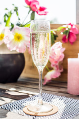 Champaign on a wooden table in the sun with flowers and candles