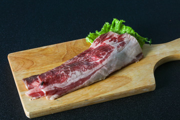 Raw beef bacon over wooden board